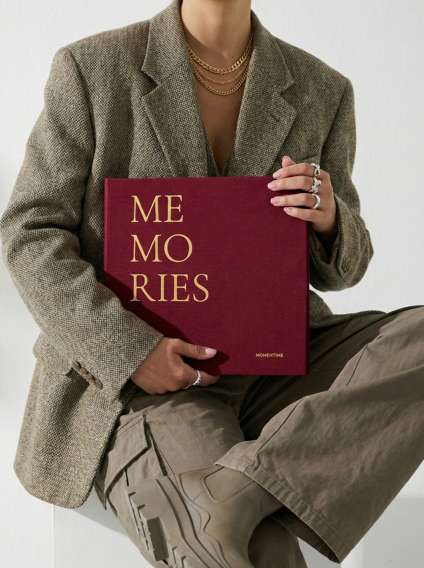 Person holding a book titled 'MEMORIES' with a plain background
