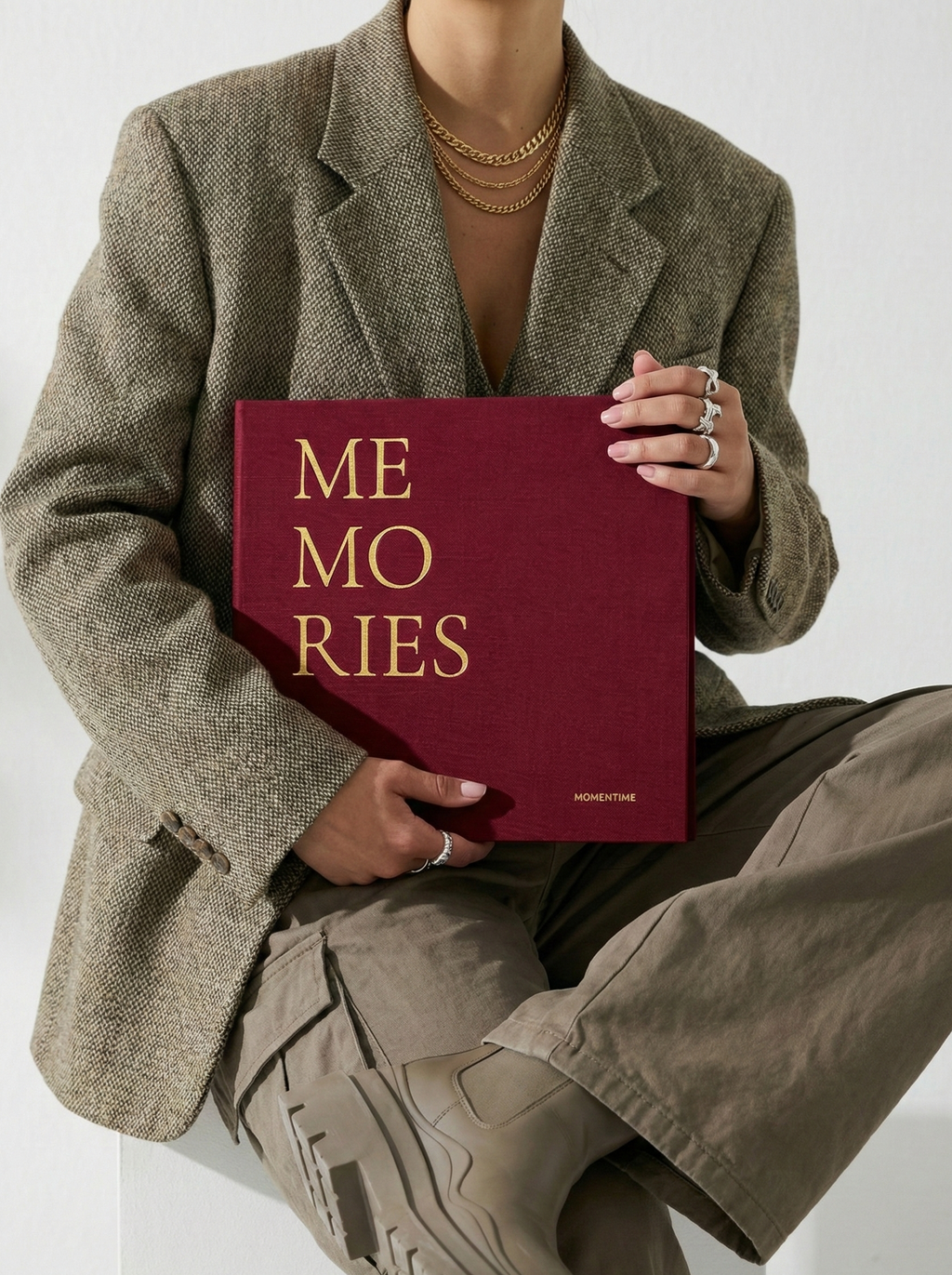Person holding a book titled 'MEMORIES' with a plain background